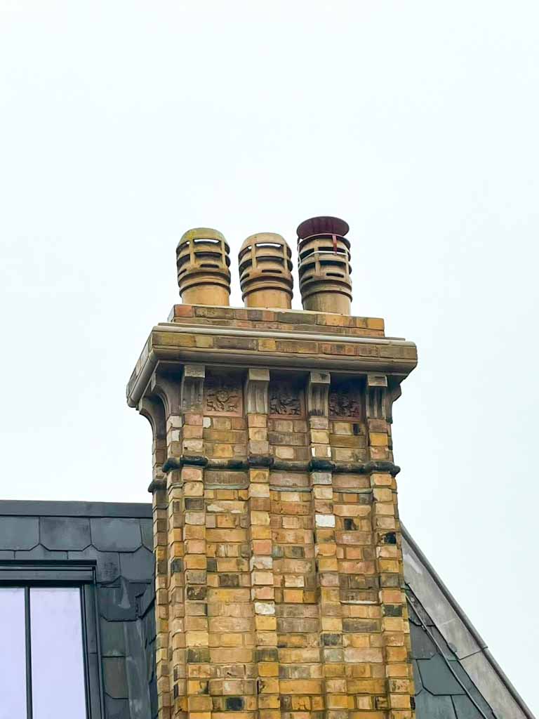 Completed ornate brick chimney with three chimney pots