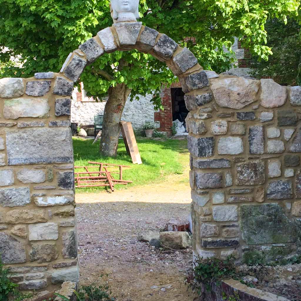 Stone wall with an arched gateway in a garden