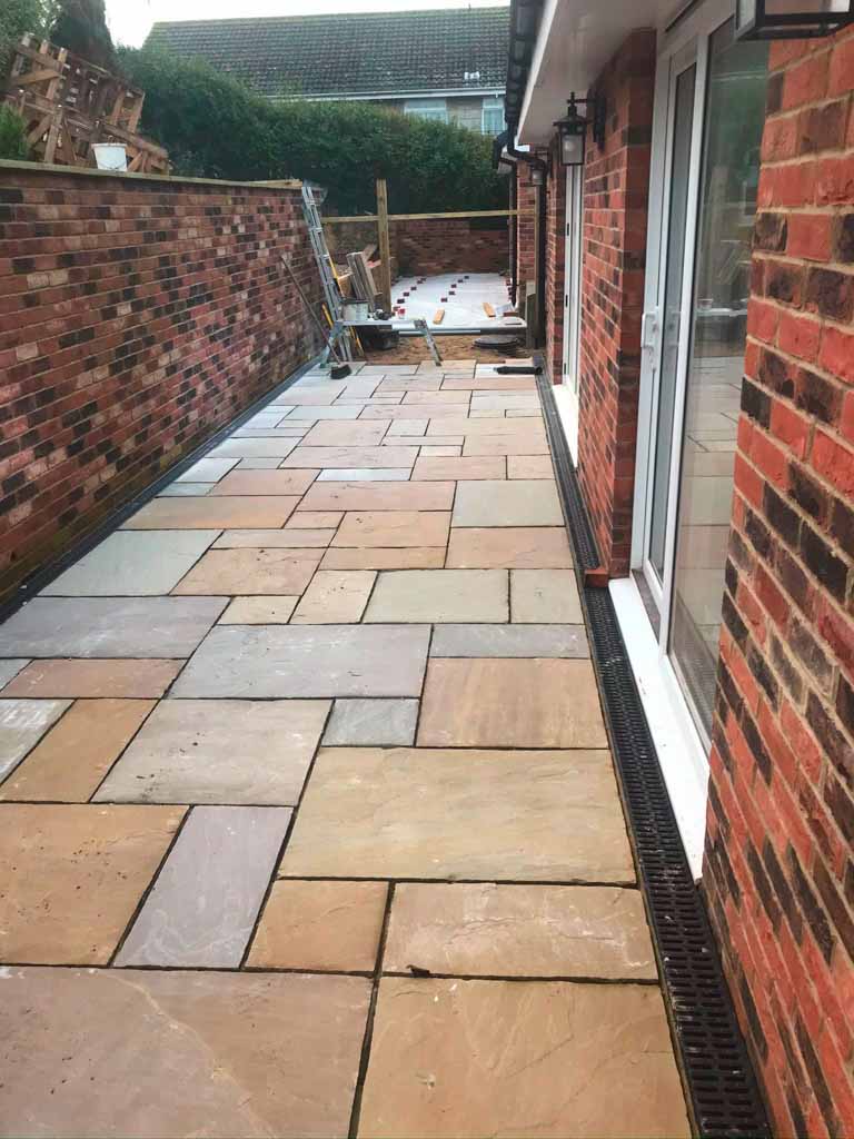 Sandstone patio laid beside a brick house