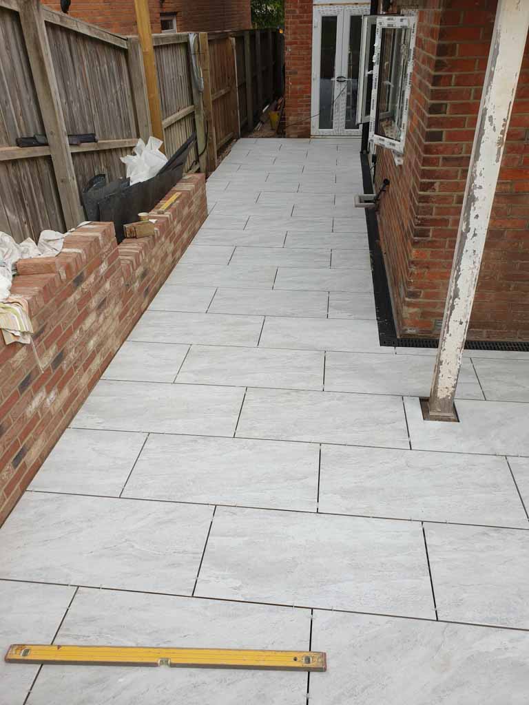 New pale stone patio beside a brick garden wall