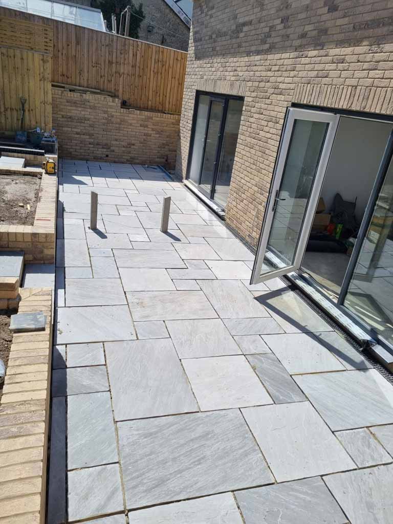 Completed pale stone patio with brick edging
