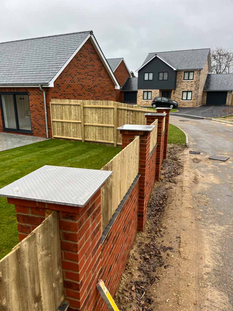Brick boundary wall and pillars beside new homes